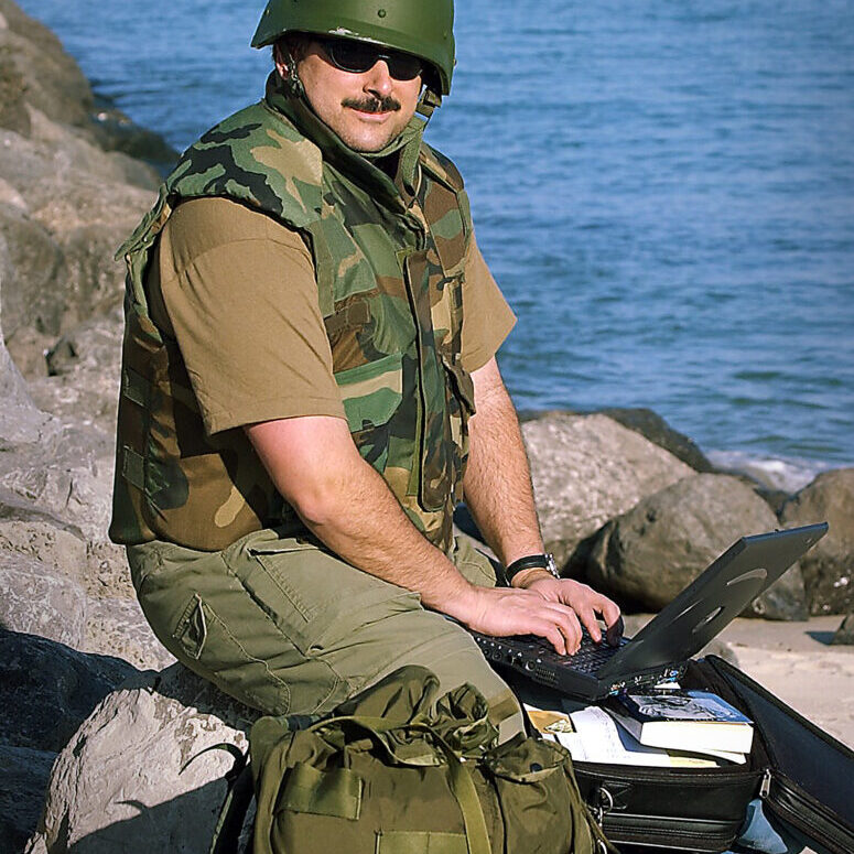 KRT PHOTO BY EDDIE LEDESMA/CONTRA COSTA TIMES (MARCH 8) KUWAIT -- Portrait of reporter Matt Schofield wearing his flack vest and kevlar helmet in Kuwait on Saturday March 8, 2003. Schofield is covering the Iraq conflict for Knight Ridder/Tribune News Service. He will be embedded with the 7th Engineers Support Battalion, 1st Marine Expeditionary Force. Photo for his profile story.    (KRT)  Kansas City Star reporter Matthew Schofield was embedded with the Marines in Iraq. Returned home and went fishing with his son, Cedric. Father's Day. CUTLINE Before leaving for Iraq, writer Schofield posed with his laptop beside the Persian Gulf. Photo by Eddie Ledesma.